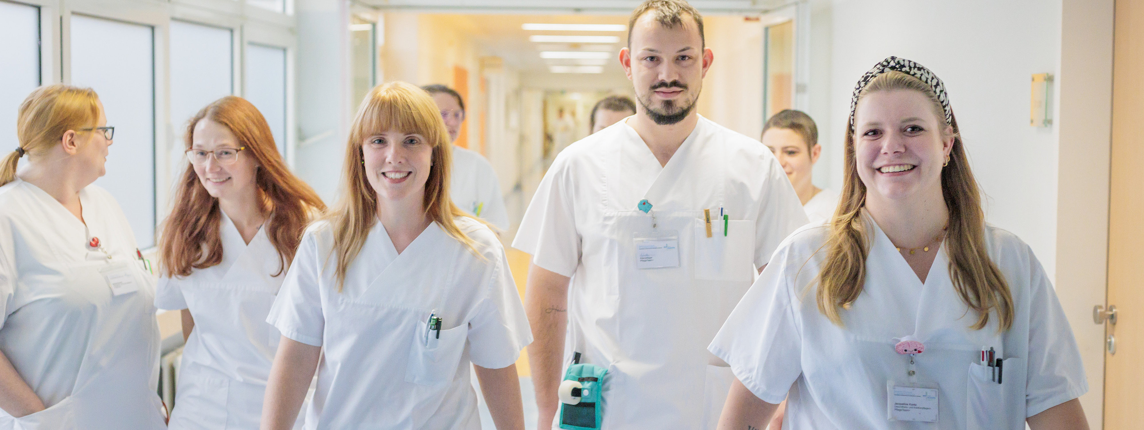 Drei medizinische Fachkräfte in blauer und lila Schutzkleidung arbeiten gemeinsam an einem Patienten mit Beatmungsgerät und medizinischen Monitoren